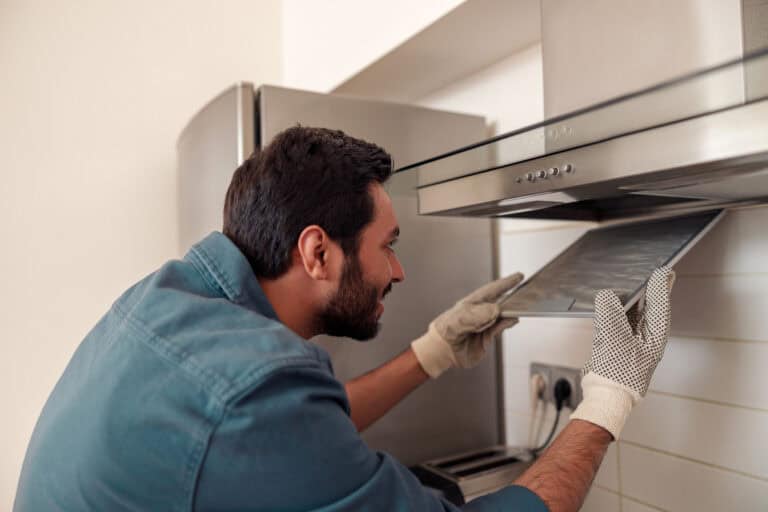 Ein Handwerker installiert eine Dunstabzugshaube